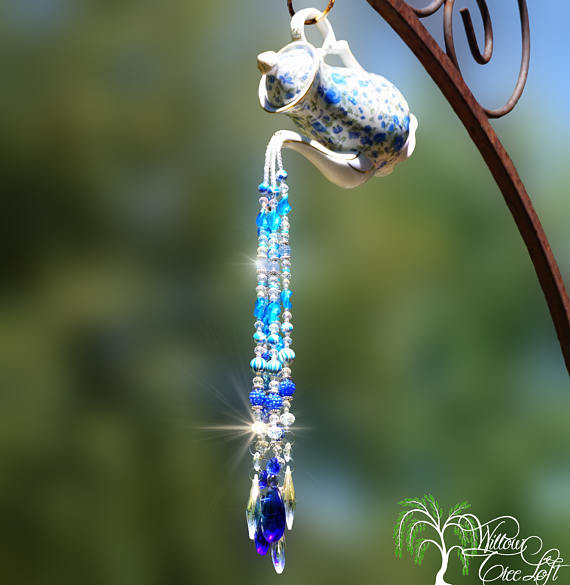 A sun catcher with a blue swarovski crystal hanging from a tree.
