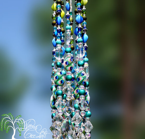 A beaded sun catcher hanging from a tree.