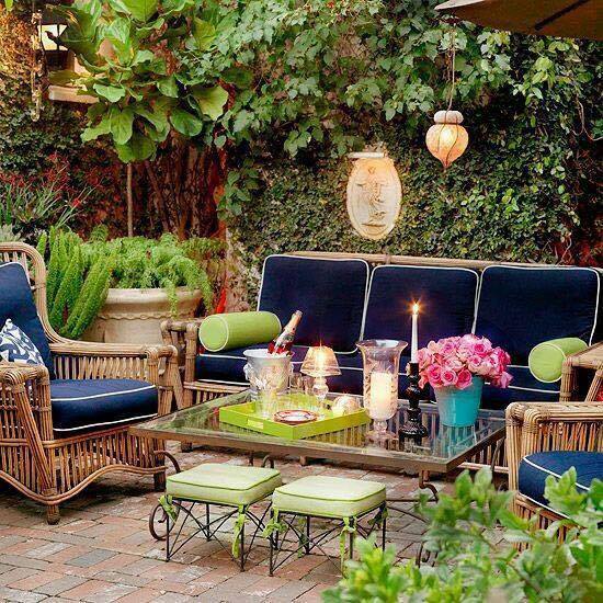 A backyard patio with wicker furniture and blue pillows.
