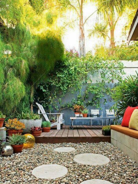 A small backyard garden with a gravel patio and potted plants.