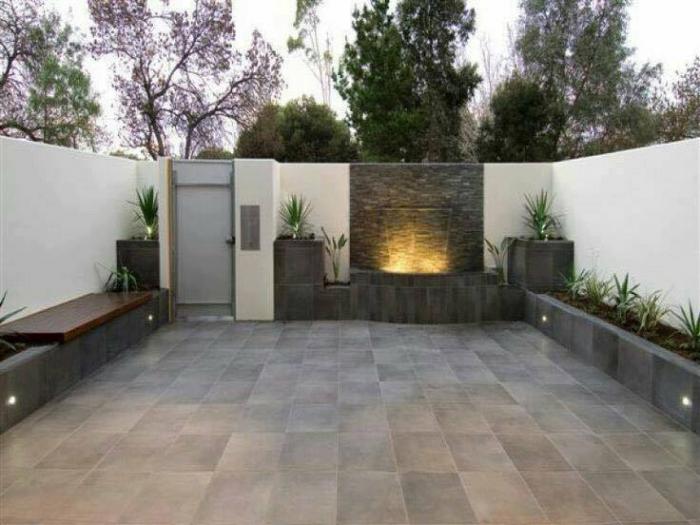 A modern backyard garden with a water feature and plants.