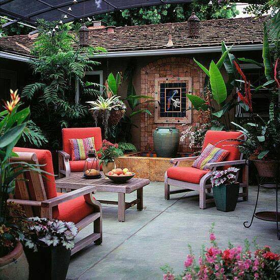 A backyard garden with red furniture and plants.