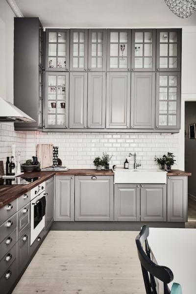 A Swedish kitchen with grey cabinets and white counter tops.