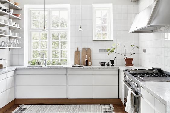 A Swedish kitchen with white cabinets and a rug.