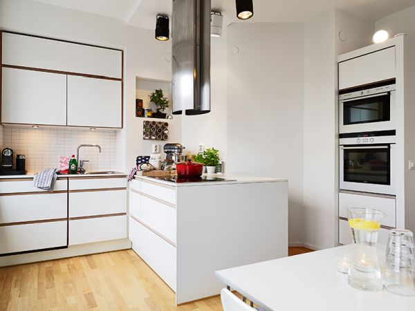 A Swedish kitchen with white cabinets and wooden floors.