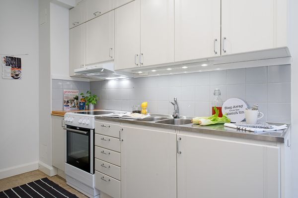 A small Swedish kitchen with white cabinets and a microwave.