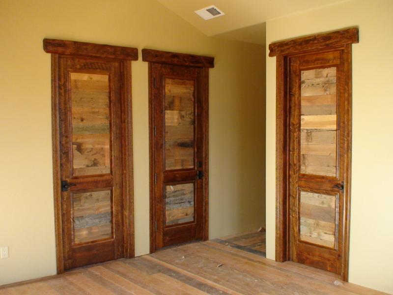 Three reclaimed wooden doors in a room with wood floors.