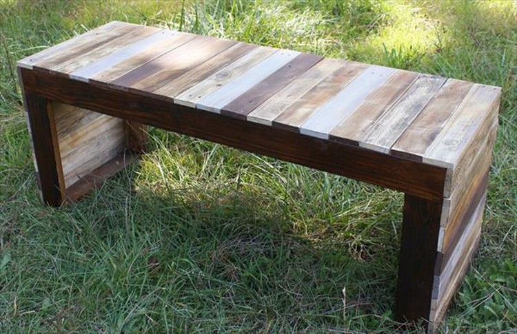 A reclaimed wood bench in the grass.