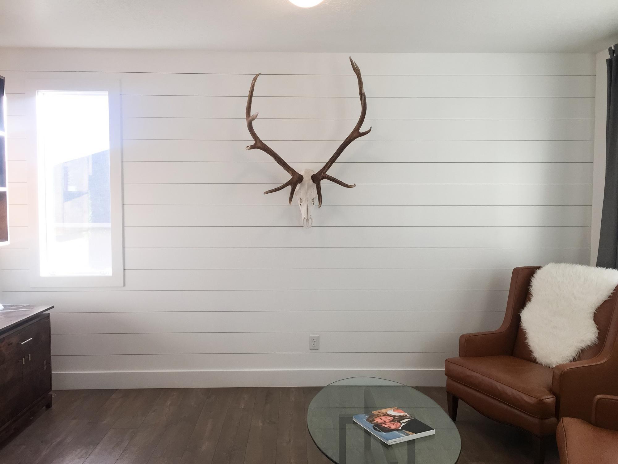 A living room with a reclaimed wood deer head on the wall.