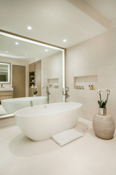 A spacious white bathroom with a large mirror.