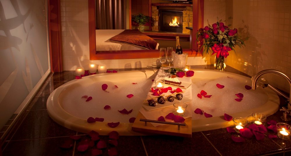 A romantic Valentine's Day decor of a bathtub filled with rose petals and candles.