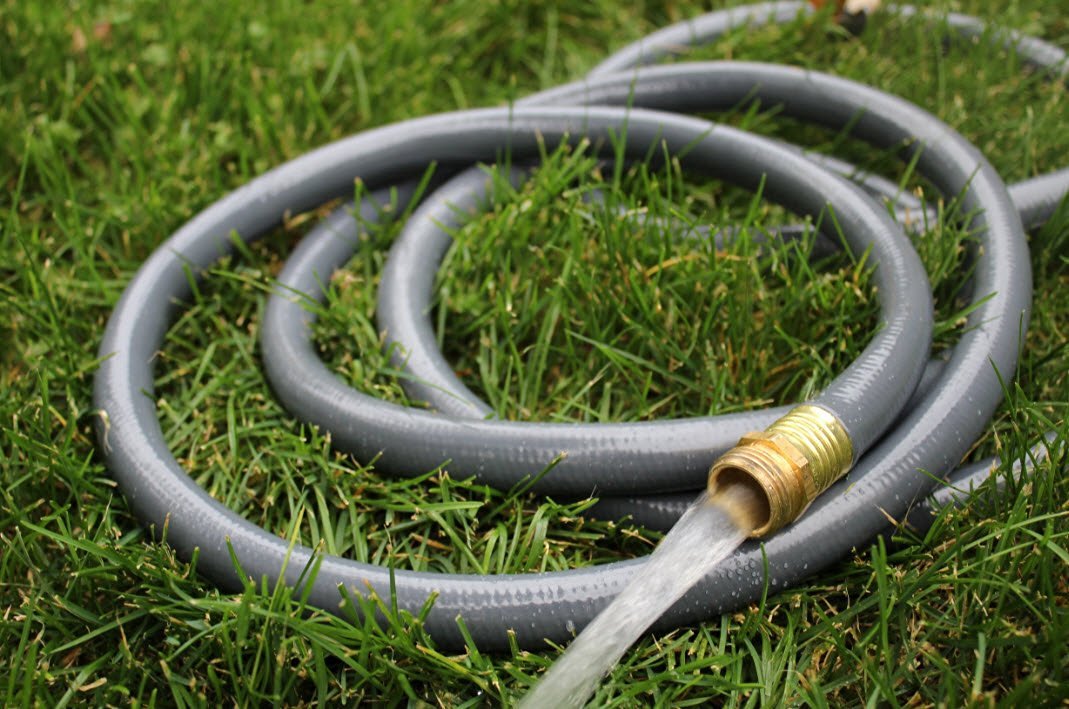 A garden hose is being used to water the grass.