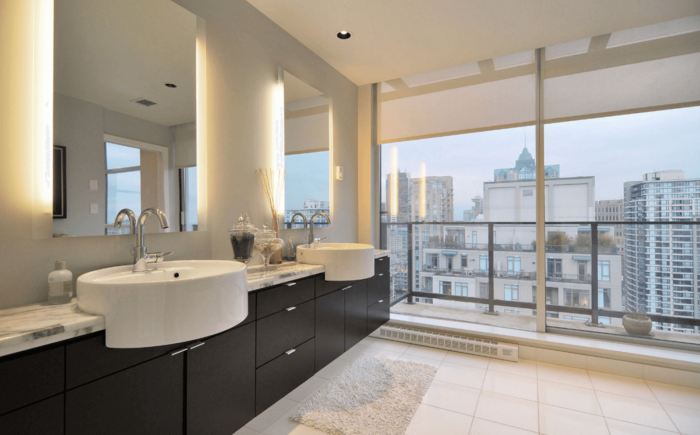 A bathroom with two sinks and a view of the city overlooking a bathroom mirror.