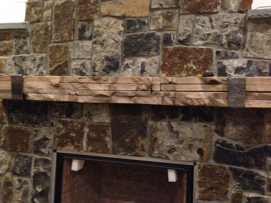 A stone fireplace with a reclaimed wooden mantle.