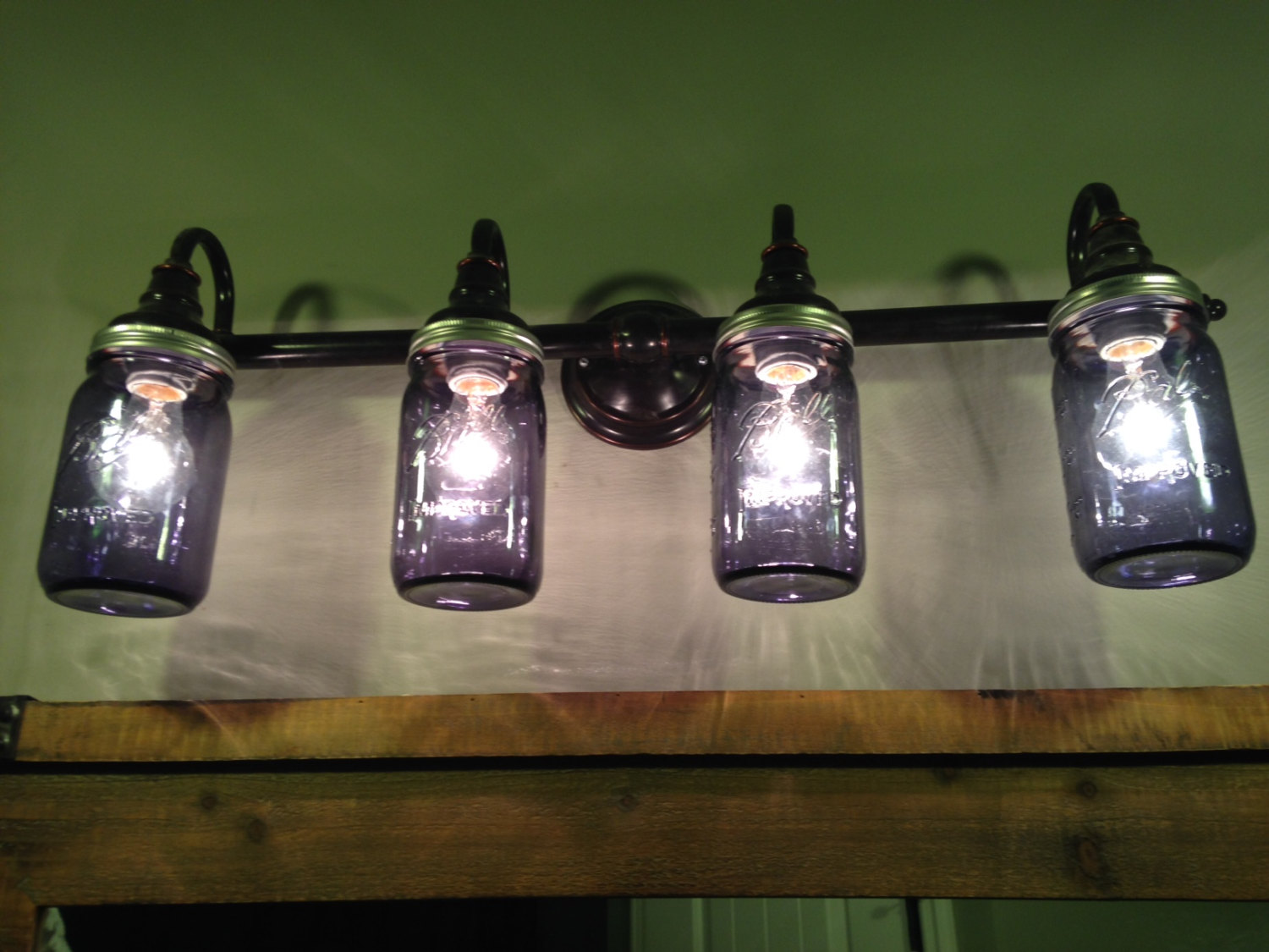 Four mason jar lights hanging on a wall.