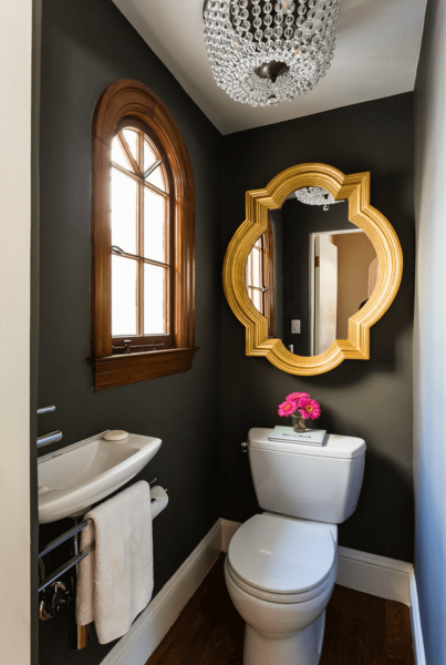 A bathroom with a gold mirror.