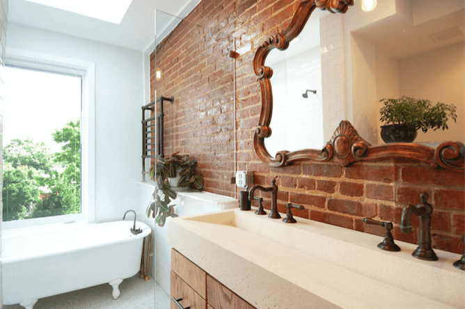 A bathroom with a brick wall and a mirror.