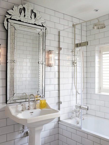 A white bathroom with a ornate mirror and sink.