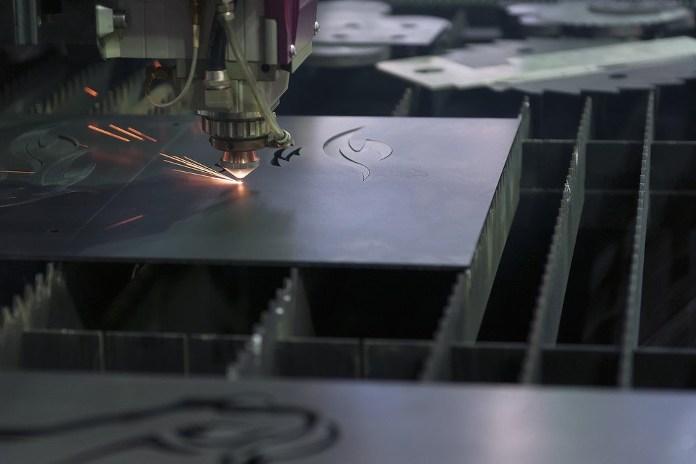 A laser cutting machine is cutting metal on a table in a factory.