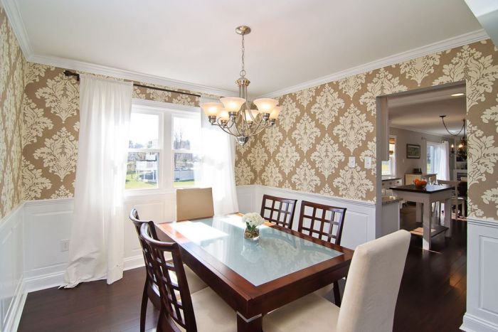 A dining room with beige wallpaper and a glass table.