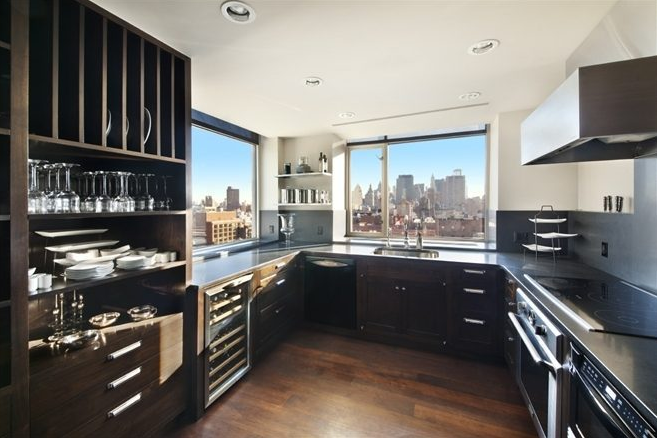A penthouse kitchen with black cabinets and a view of New York City.