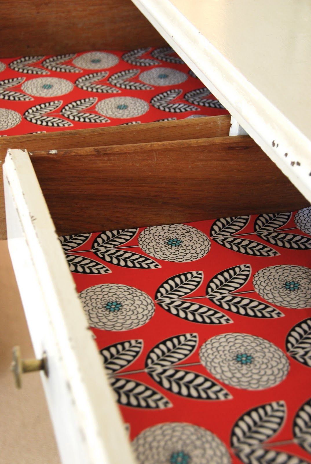 A drawer made from leftover wallpaper with a red and black pattern.