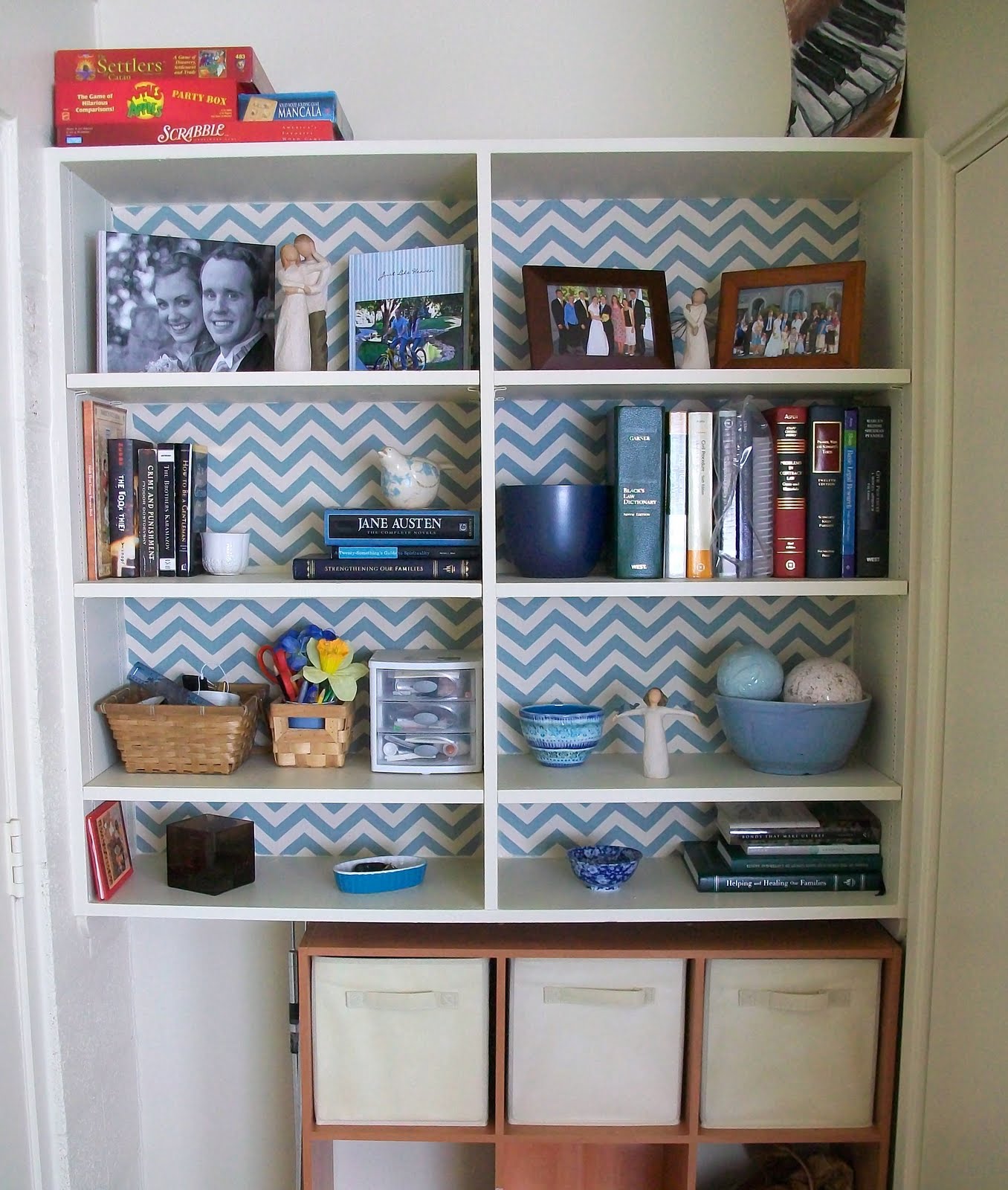 A bookcase with leftover blue and white chevron patterned wallpaper.