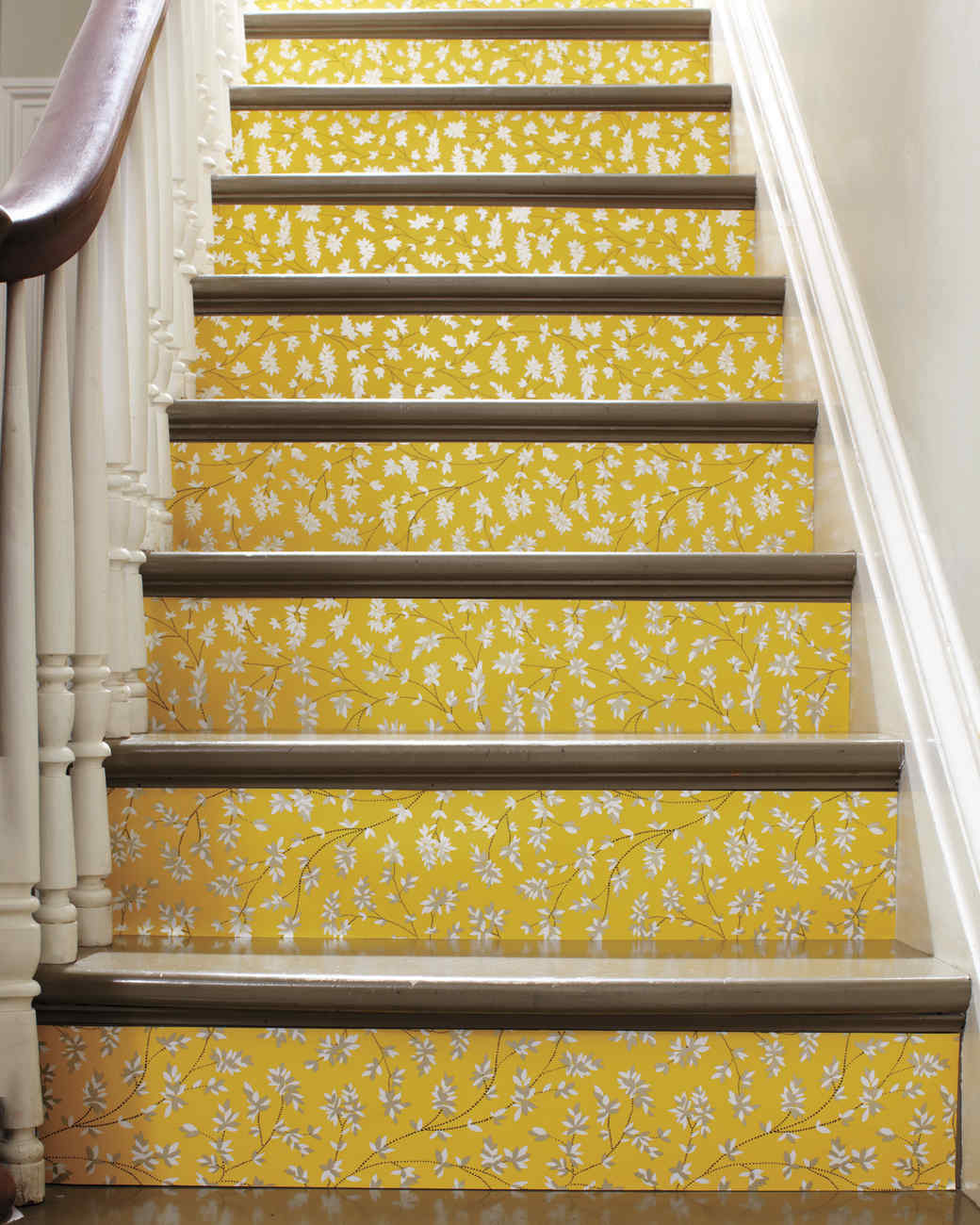 A yellow stair tread with a leftover wallpaper.