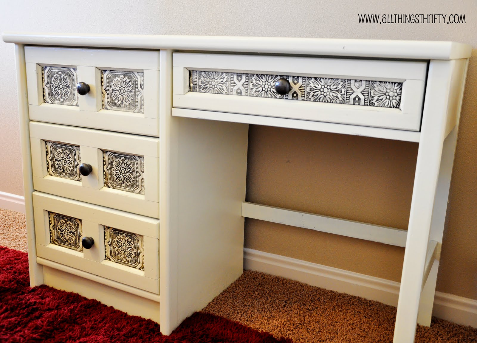 A white desk with drawers and a rug made from leftover wallpaper.