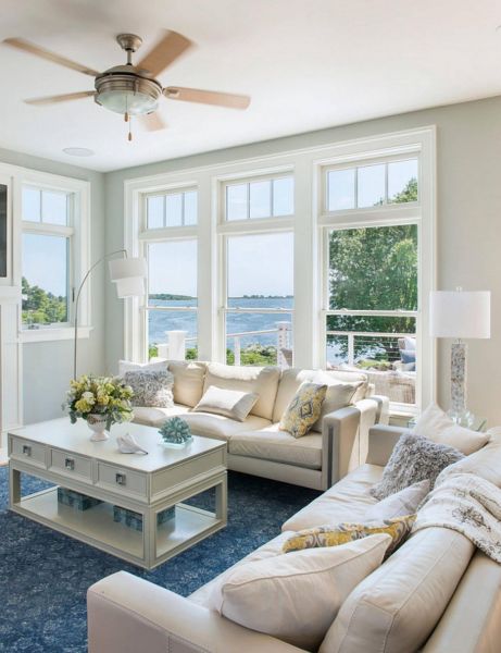 A beach cottage style living room with large windows overlooking the ocean.