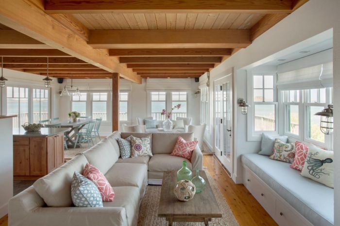 A beach cottage style living room with wooden beams and couches.