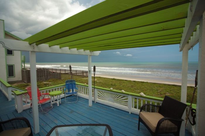 A beach cottage-style deck overlooking the ocean with a green canopy.