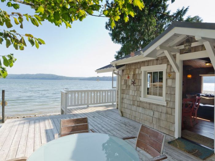 A cozy beach cottage on the water with a table and chairs.