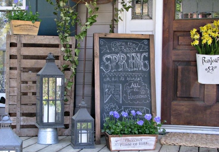 Front porch decorated with chalkboard and potted plants.
