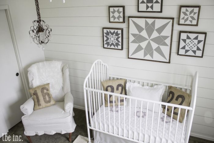 A gender neutral nursery with a crib, chair and wall art.