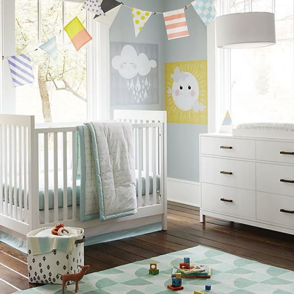 A gender neutral nursery with a crib, dresser, and a rug.