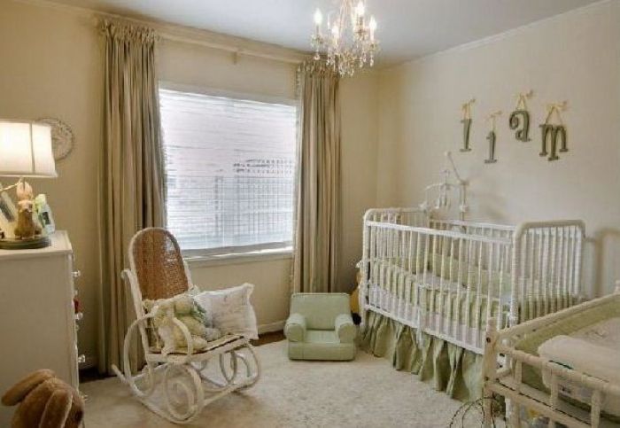 A gender neutral nursery with a crib, dresser, and a chandelier.