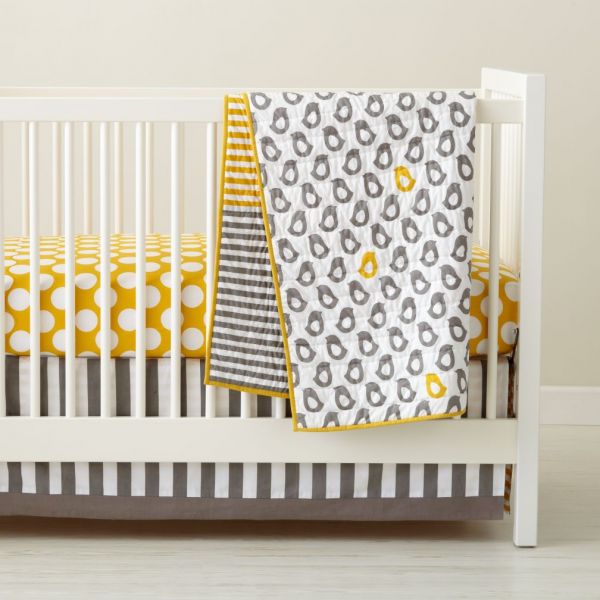A gender neutral baby crib with yellow and grey polka dot bedding.