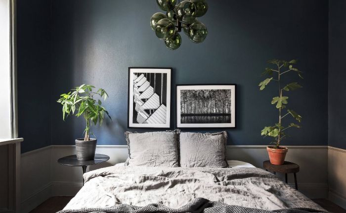 A wabi sabi style bedroom with dark blue walls and a bed.