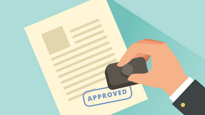 A person is holding a rubber stamp on a document for HOA Approval.