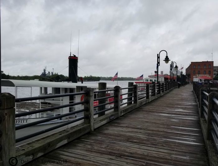 A wooden pier leading to a boat in Wilmington on a rainy day.