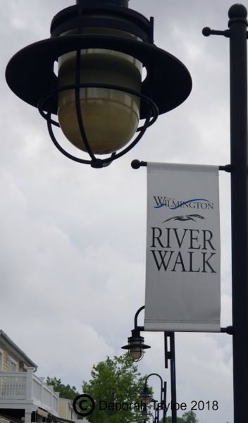 A street light in Wilmington with a sign that says river walk.