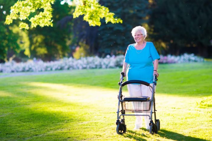 An elderly woman using a walker to walk in a park, Senior citizens.