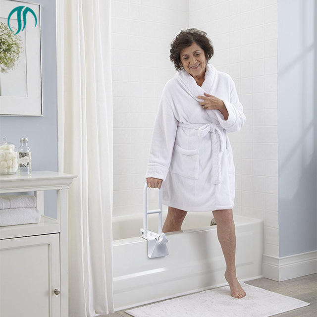 A senior woman in a bathrobe standing next to a bathtub.
