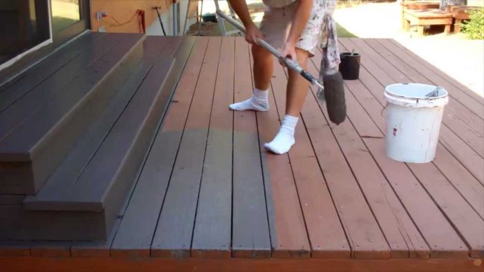 A man DIY painting a wooden deck.