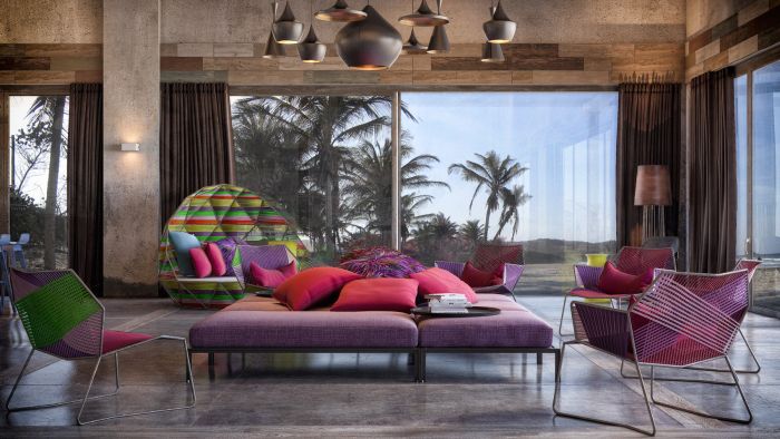 A living room with colorful island style furniture and a view of the ocean.