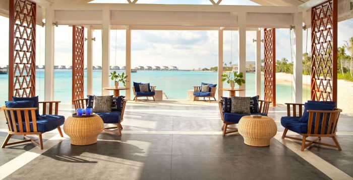 A lounge area with island style blue chairs and a view of the ocean.