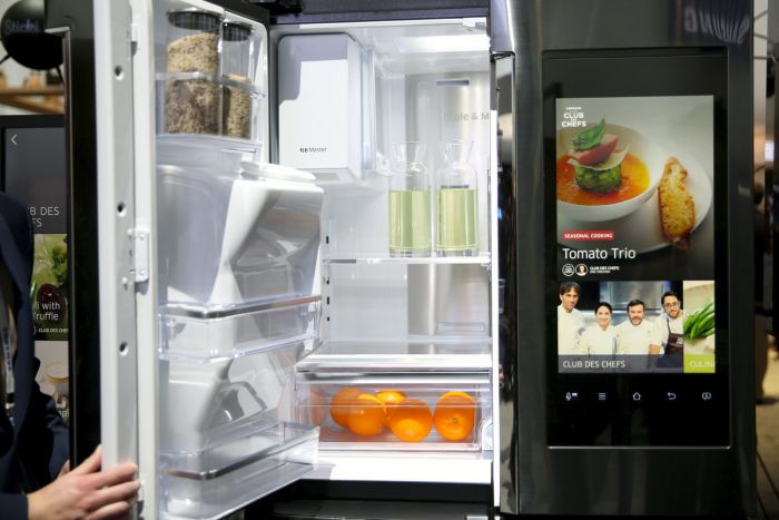 A man is opening a refrigerator door in a modern kitchen design.