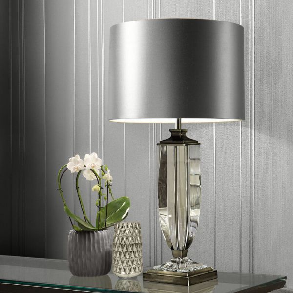 A metallic lamp on a table next to a vase.