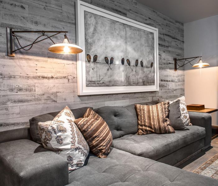 A gray couch with a wood accent wall in a living room.